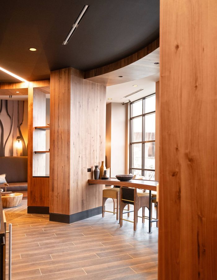 Madison West Elm apartments Modern lounge with wood accents, large windows, two chairs, and natural light creating a cozy atmosphere.