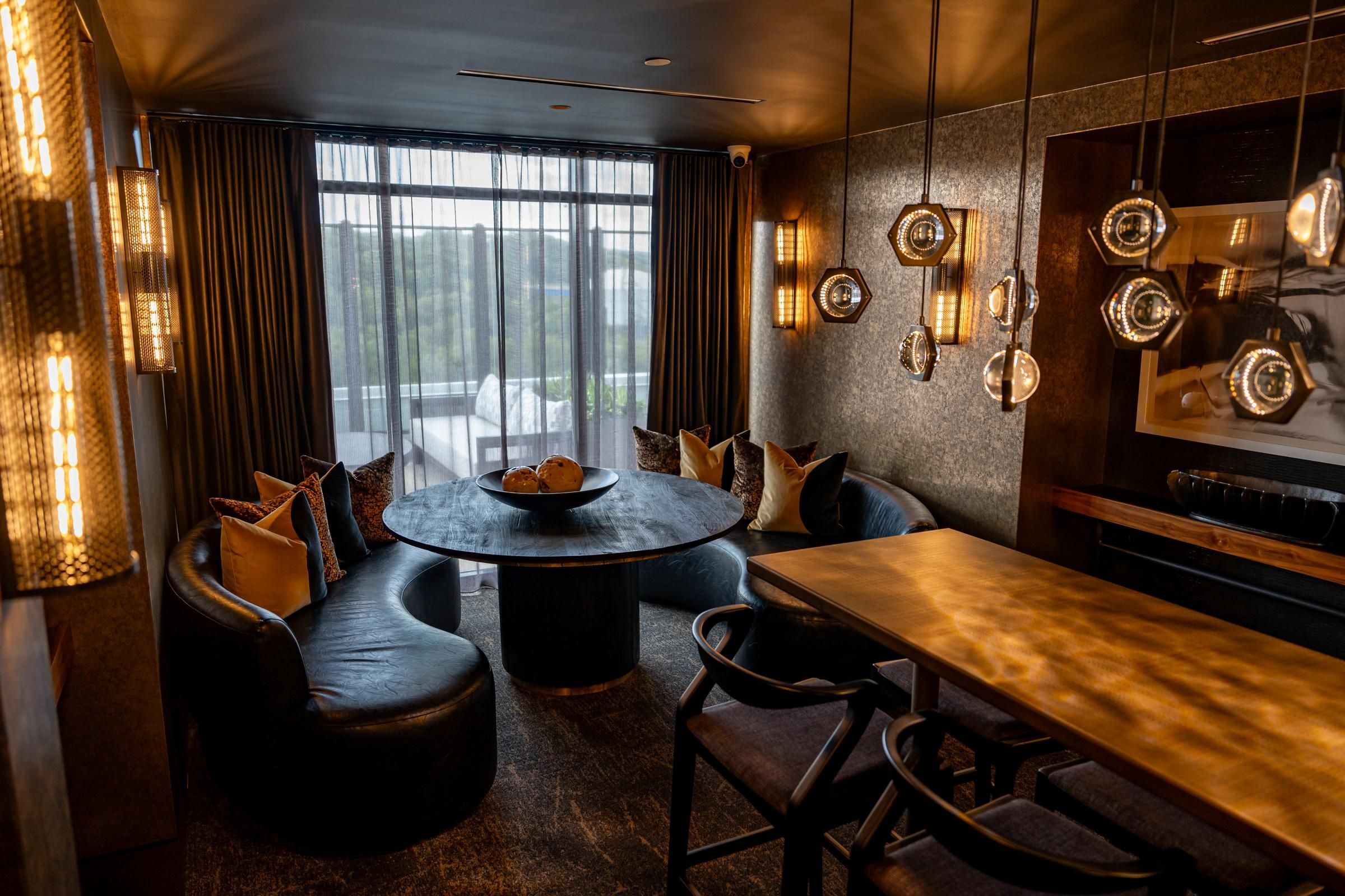 Madison West Elm apartments Modern dining room with round table, curved leather seats, and unique pendant lighting by large window.