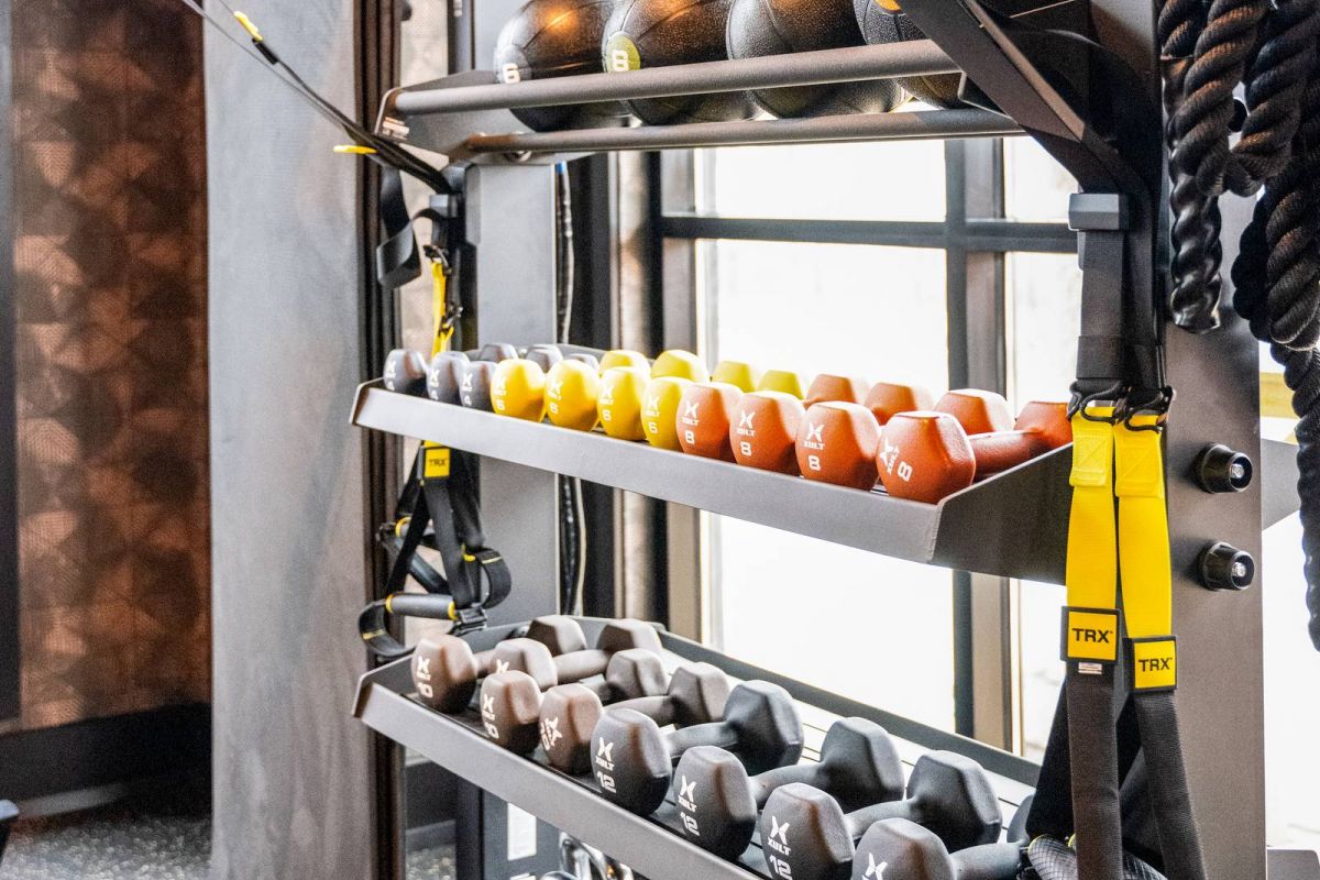 Madison West Elm apartments A gym rack with medicine balls, dumbbells, kettlebells, and TRX suspension straps.