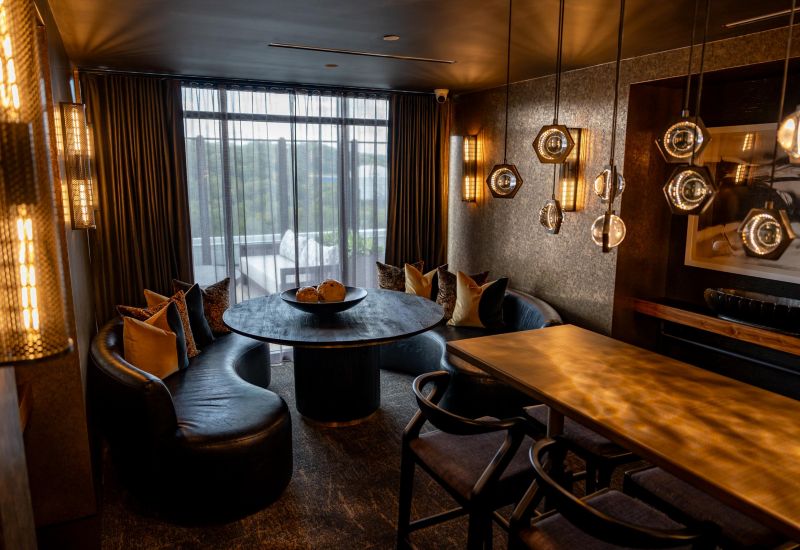 Madison West Elm apartments Modern dining room with round table, curved leather seats, and unique pendant lighting by large window.
