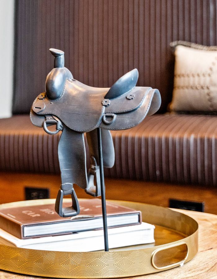 Madison West Elm apartments A small black horse saddle sculpture sits on books atop a gold tray on a wooden coffee table.